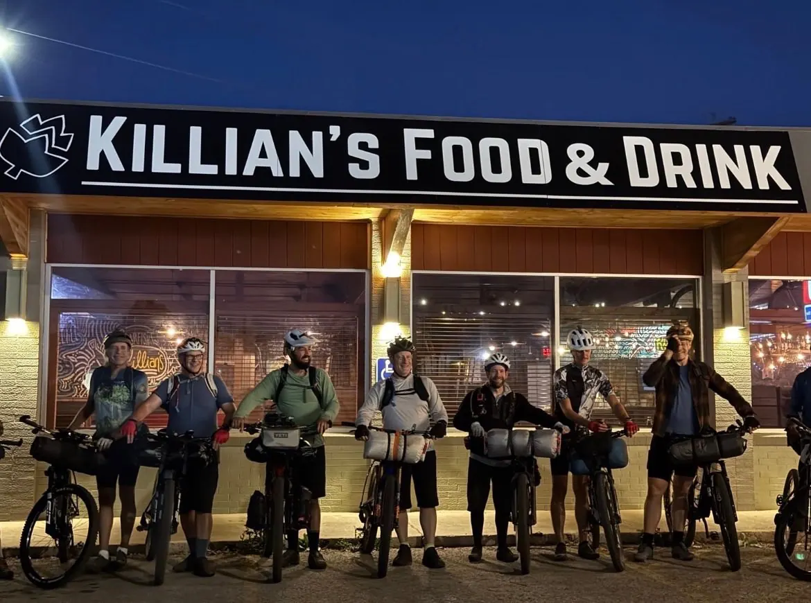 Group of cyclists with their bikes gathered outside the Killian's storefront in Spearfish, SD